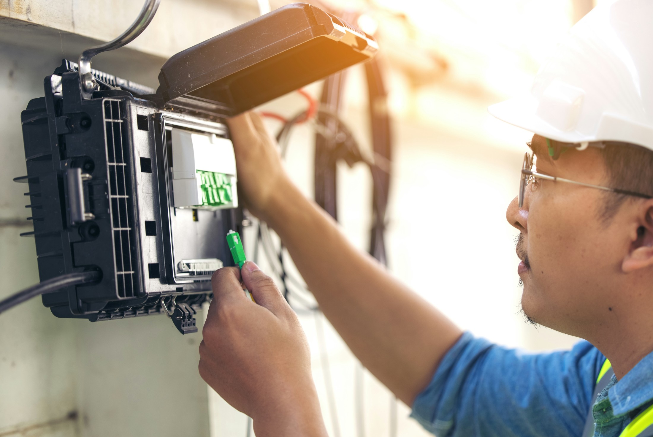 Techniker bei der Montage eines Glasfaserverteilers im FTTH-Netzausbau